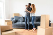 © Vadim Pastuh - Young family buy a new, house, rent an apartment, got a mortgage. Mixed-race spouses with infant moving to new house. Loving young multiracial parents carrying baby girl, look at her and smiling
