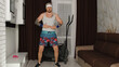 © Andrii Iemelianenko - Funny fat sportsman man athlete in sportswear making sport fitness exercise. Retro bearded gray hair hipster guy showing cardio exercises for weight loss in living room at home. Humor joke, motivation