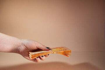 Female hand holding a bundle of money with colorful background. Top view of one thousand Argentine peso bills. Salary concept with empty space for your design