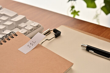 Poster - A sticky note labeled SSL is taped to the edge of a notebook on the desk.That's an acronym for Secure Sockets Layer.