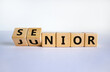 From junior to senior symbol. Turned cubes and changed the word 'junior' to 'senior'. Beautiful white background, copy space. Business and junior or senior concept.