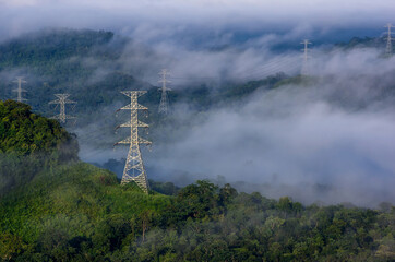 Wall Mural - high voltage power transmission towers in fog on mountain mae moh lampang.