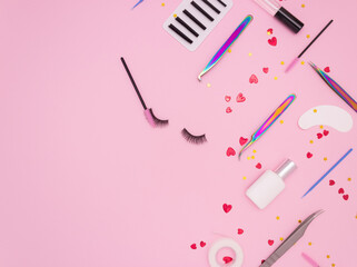 Wall Mural - Eyelash extension tools, artificial eyelashes and red hearts on a pink background. Tools for the lashmaker. Top view, copyspace.