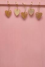 Many Small Hearts Carved From Wood Hang Pinned To Pink Wooden Background. Copy Space, Place For Your Text. Valentin's Day Concept, Love, Wedding