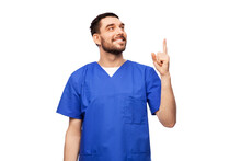 Healthcare, Profession And Medicine Concept - Doctor Or Male Nurse In Blue Uniform Pointing Finger Up Over White Background