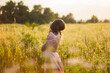 © pijav4uk - Young woman covered with long hair standing in the wildflowers field in the long pink dress on a warm summer evening. Joyfull summer walking. Beauty and nature.