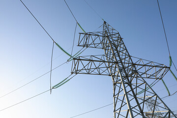 High voltage tower against blue sky on sunny day, low angle view