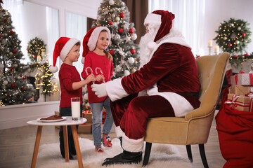 Wall Mural - Santa Claus giving candy canes to children in room decorated for Christmas