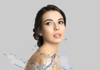 Poster - Beautiful young woman and splashing water on light grey background. Spa portrait