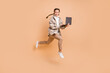 © deagreez - Full size photo of young happy smiling excited positive girl running in air hold laptop isolated on beige color background
