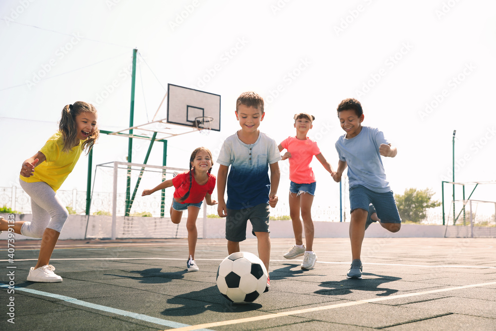 Cute children playing soccer outdoors on sunny day. Summer camp - obrazy, fototapety, plakaty 