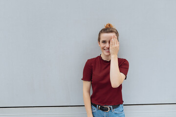 Wall Mural - young laughing woman covering her eye with one hand