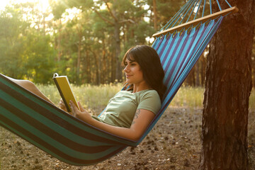 Poster - Woman with book resting in comfortable hammock outdoors