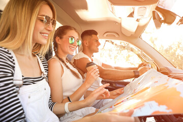 Wall Mural - Happy friends with map in car on road trip