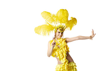 Wall Mural - Pointing. Beautiful young woman in carnival masquerade costume with yellow feathers dancing on white background. Concept of holidays celebration, festive time, dance, party, happiness. Copyspace