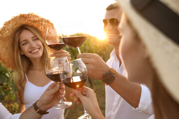 Wall Mural - Friends clinking glasses of red wine at vineyard on sunny day, closeup