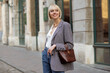 © Victoria Fox - Outdoor, street style photo of happy smiling elegant woman wearing trendy houndstooth blazer, holding brown faux reptile leather bag. Copy, empty space for text