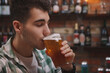 © Ihor - Close up of a handsome young man sipping beer from his glass at beer pub