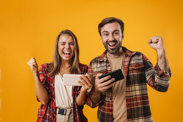 Wall Mural - Couple making winner gesture while playing video game on cellphones