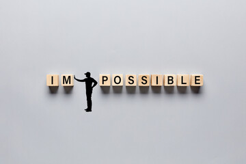 Wall Mural - Silhouette of a man transforming the word impossible into possible by pushing away the letters