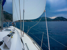 Aboard A Sailboat Yacht With Main Sail And Genoa On Ocean Sea With Mountain Background