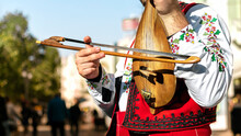 Bulgarian Folk Musician - Violinist In Traditional National Costume Plays An Old Stringed Instrument - Gadulka On Street Of Plovdiv City, Bulgaria. Bulgarian Folklore And Culture. Street Performer