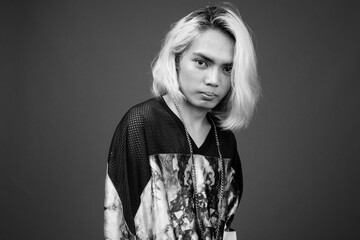 Young Asian man wearing stylish clothes against gray background