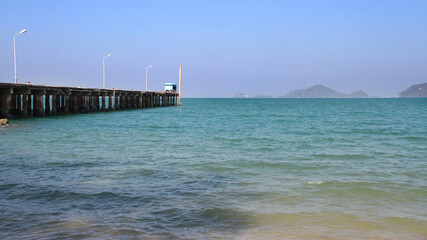 a bridge jutting into a bright blue sea with clear skies and blue houses.