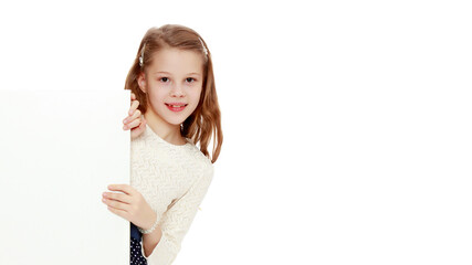 A little girl is looking from behind an empty banner.