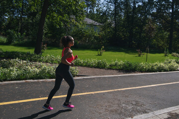  Side view of a woman runner jogging on a running way in the park. Fitness outdoor concept. Cardio training