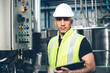 © winnievinzence - Portrait of engineer foreman holding clipboard in industrial factory. worker in safety uniform working at construction site. heavy machine technology industry concept. copy space