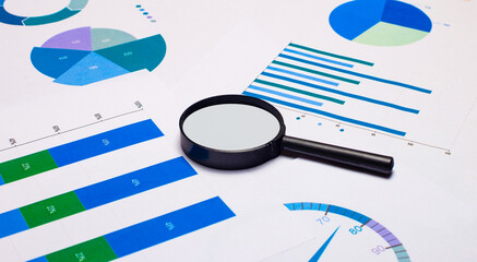 The magnifying glass is on the bright graphs and diagrams. Business concept