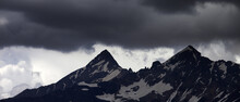 Panoramic View On Storm Clouds In High Snowy Mountains
