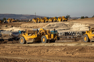 Wall Mural - Earth moving equipment at a construction grading site with other tractors lined up in the background