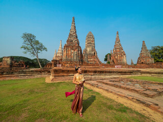 woman in Thai traditional costume with ancient pagoda at temple at Ayutthaya, Thailand (Wat Chai Wattanaram), wide angle view