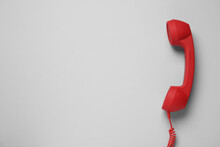 Red Corded Telephone Handset On Light Grey Background, Top View. Hotline Concept