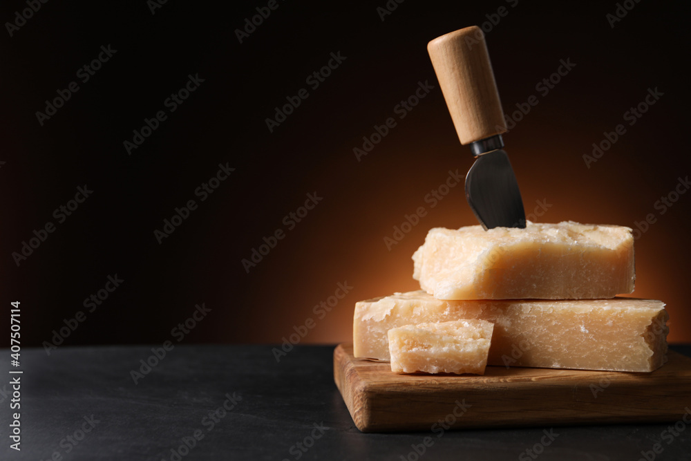 Delicious parmesan cheese with knife on black table. Space for text - obrazy, fototapety, plakaty 