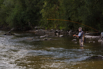 Fly fisherman using flyfishing rod in beautiful river.