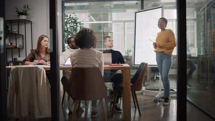 Aufkleber - Project Manager Makes a Presentation for a Young Diverse Creative Team in Meeting Room in an Agency. Colleagues Sit Behind Conference Table and Discuss Business Development, User Interface and Design.