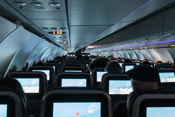 Plane cabin with passengers by night lit from screen (display) light