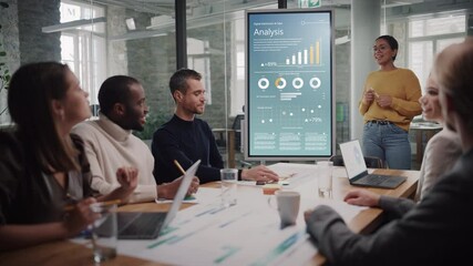 Aufkleber - Project Manager Makes a Presentation for a Young Diverse Creative Team in Meeting Room in an Agency. Colleagues Sit Behind Conference Table and Discuss Business Development, Sales Analysis and Design.