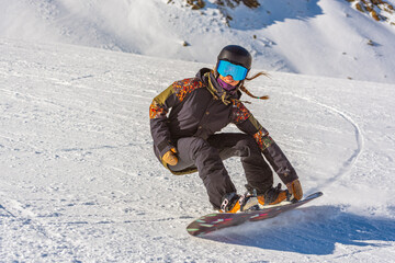 Young woman snowboarder in motion on snowboard in mountains