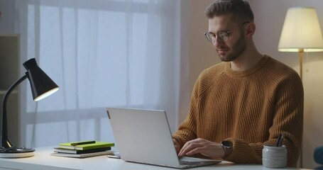 adult man is typing and sending message by internet, using laptop, sitting at living room, using social networking and email