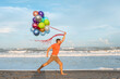 © Maria - happy guy running along the beach with colored balloons. man holding a lot of colored balloons.