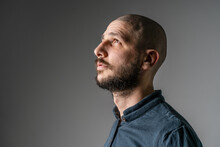 Side View Close Up Portrait Of Adult Caucasian Man With Beard And Short Hair Looking Up Thoughtful With Copy Space - Studio Shot