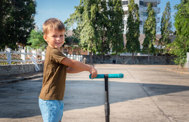 Portrait of a child with a scooter outside.