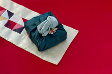 Korean Traditional Wrapping Cloth Made Of Silk(bojagi) And Ornaments With Copy Space On Red Cloth Background. 
