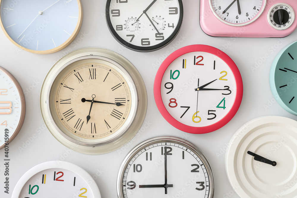 Different clocks hanging on light wall