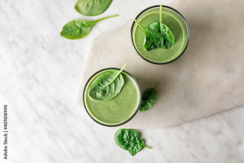Glasses of healthy spinach smoothie on light background