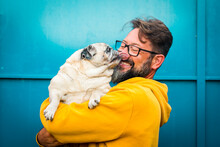My Best Friend Dog Concept With Funny Scene Adult Man With Beard And Pug Dog Kissing Him On The Face - People And Animals Have Fun And Love Together In Friendship